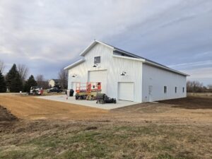 A white post frame barn looking building.