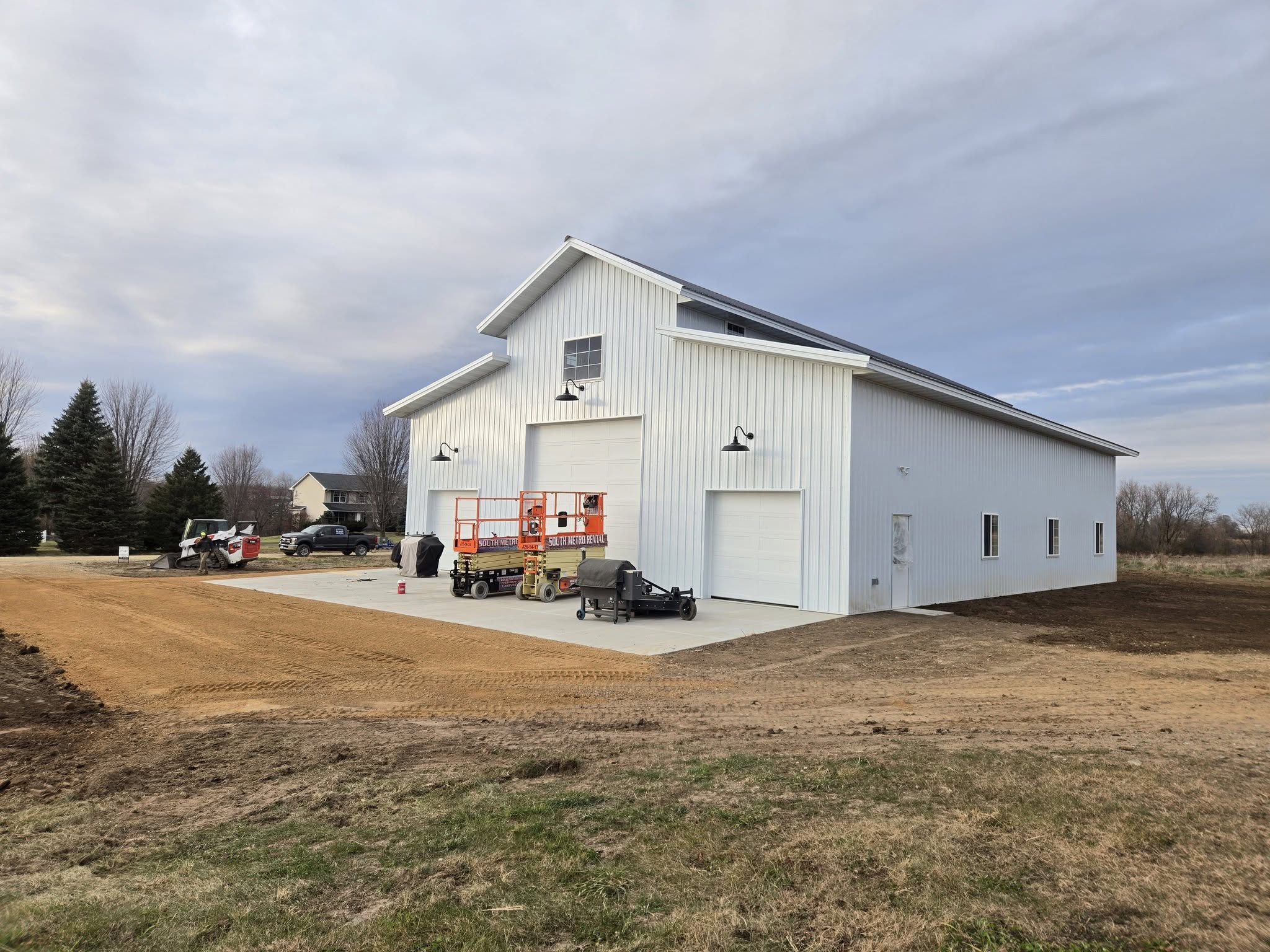 A white post frame barn looking building.